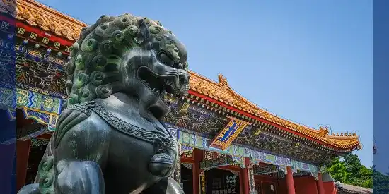 Temple en chine de couleurs vives avec en premier plan une statue d'un lion
