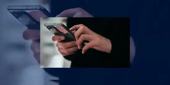 Personne habillée en noir utilisant un smartphone pour illustrer l'arnaque au vishing