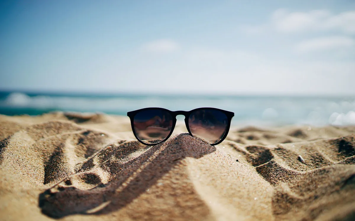 photographie d'une plage avec des lunettes de soleil symbolisant la sérénité d'une retraite bien préparée et anticipée